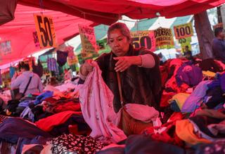 Une femmes inspecte des articles dans un marché de vêtements d’occasion à Mexico, en mars 2024.